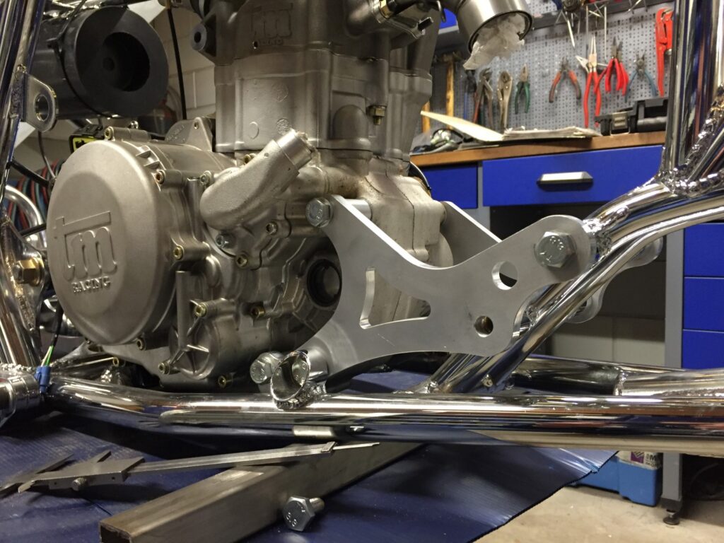 TM Racing motorblok met CNC-gefreesde aluminium motorsteun gemonteerd in gepolijst buizenframe.