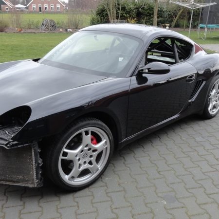 Porsche Cayman in beginfase van ombouw tot raceauto, met zichtbare rolkooi en verwijderde voorbumper
